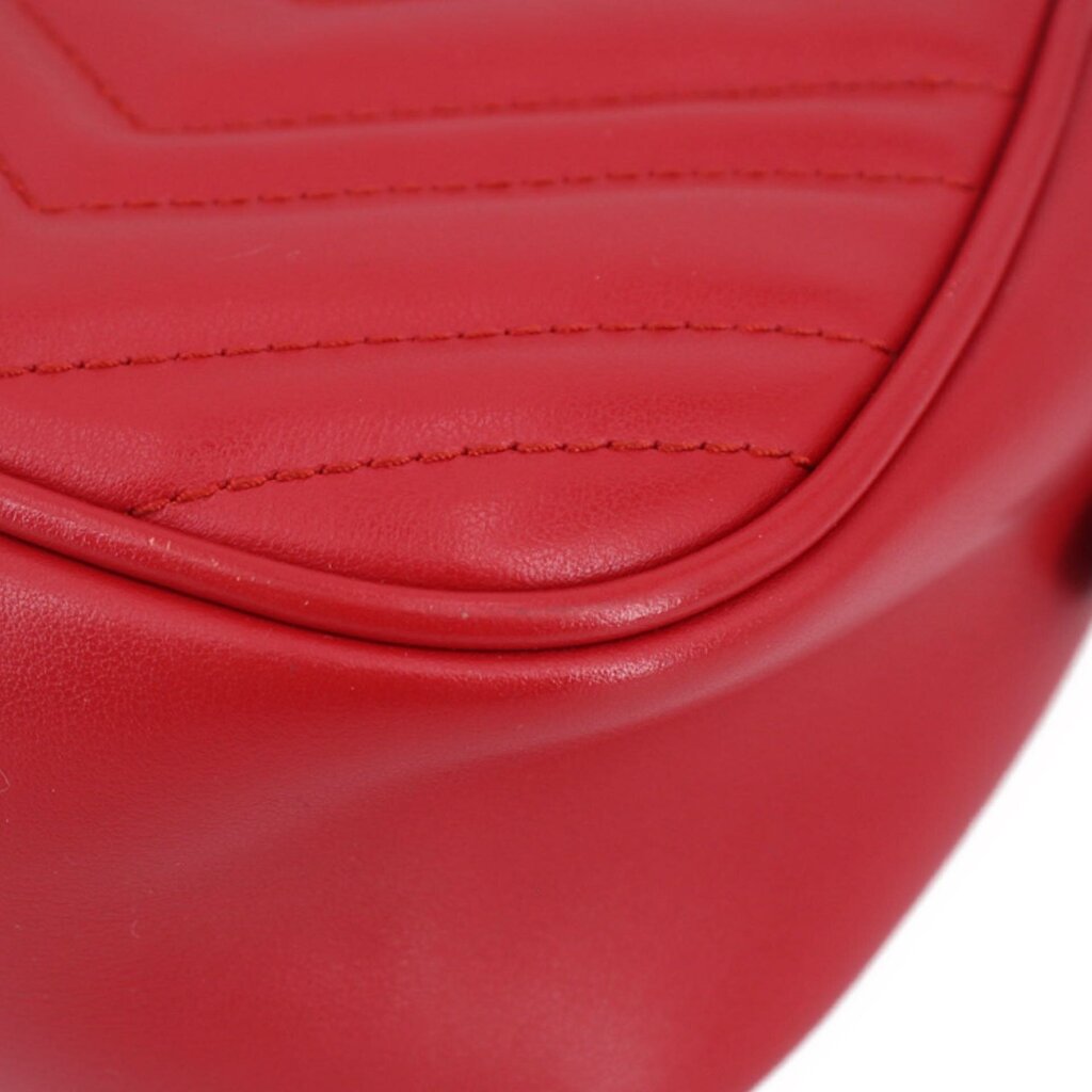 Close-up of red quilted leather camera crossbody bag stitching and curved seam