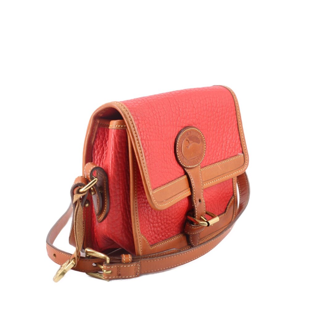 Red crossbody bag side view with tan trim, front strap buckles, and gold-tone hardware
