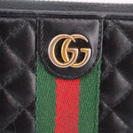 GG logo plaque on black quilted leather with green and red Web stripe, close-up.