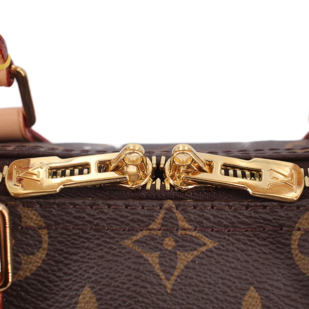 Louis Vuitton monogram bag clasp close-up, gold-tone hardware on dark brown canvas