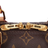 Louis Vuitton monogram bag clasp close-up, gold-tone hardware on dark brown canvas