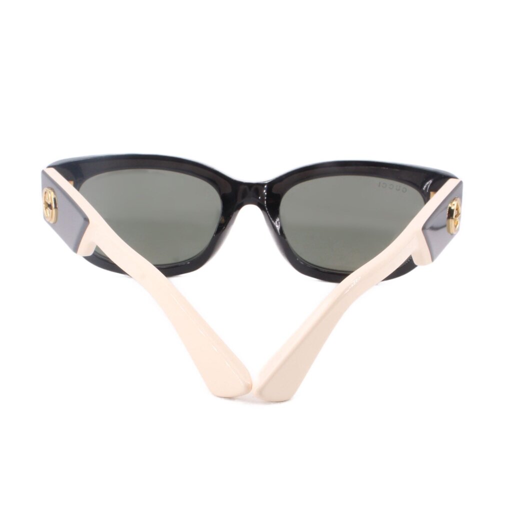 GUCCI black sunglasses with cream temple tips, gold logos, and dark lenses