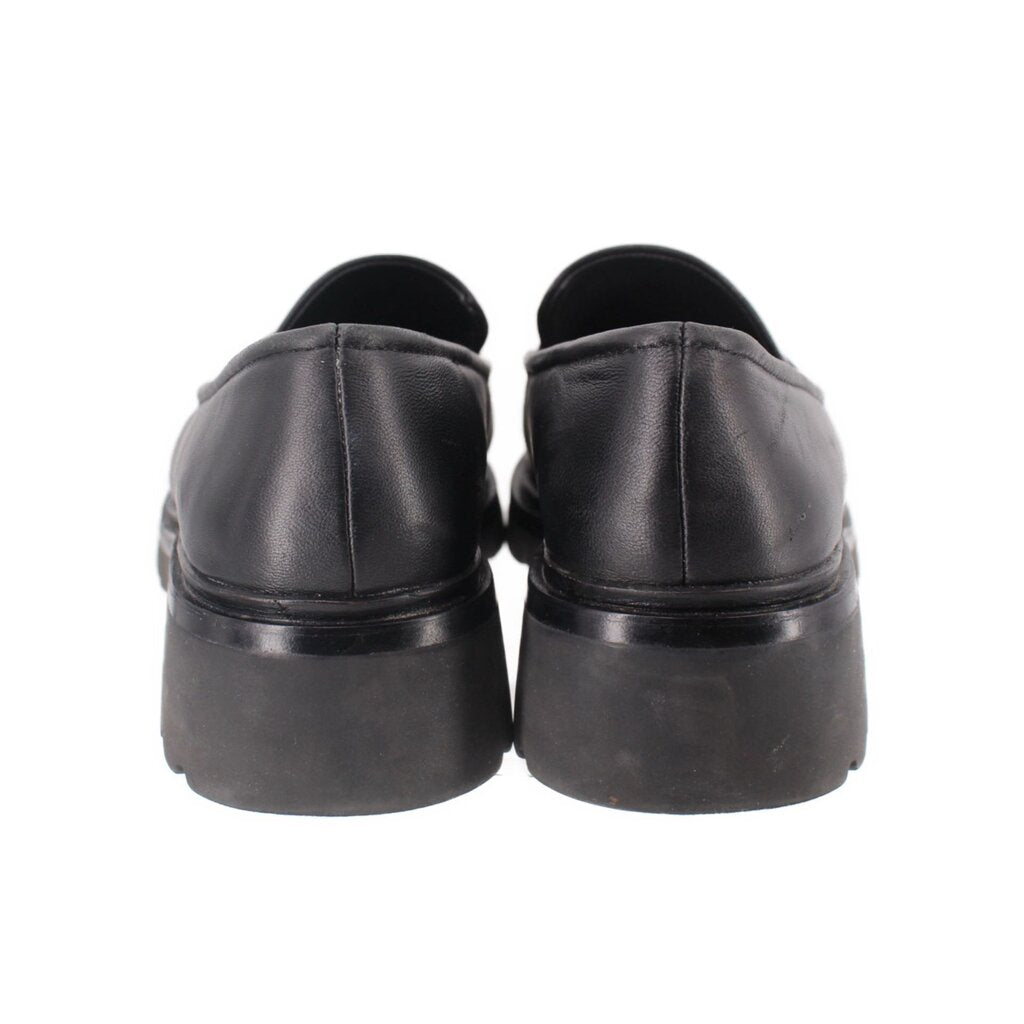 Back view of black leather loafers with low stacked heel and rounded heel counters
