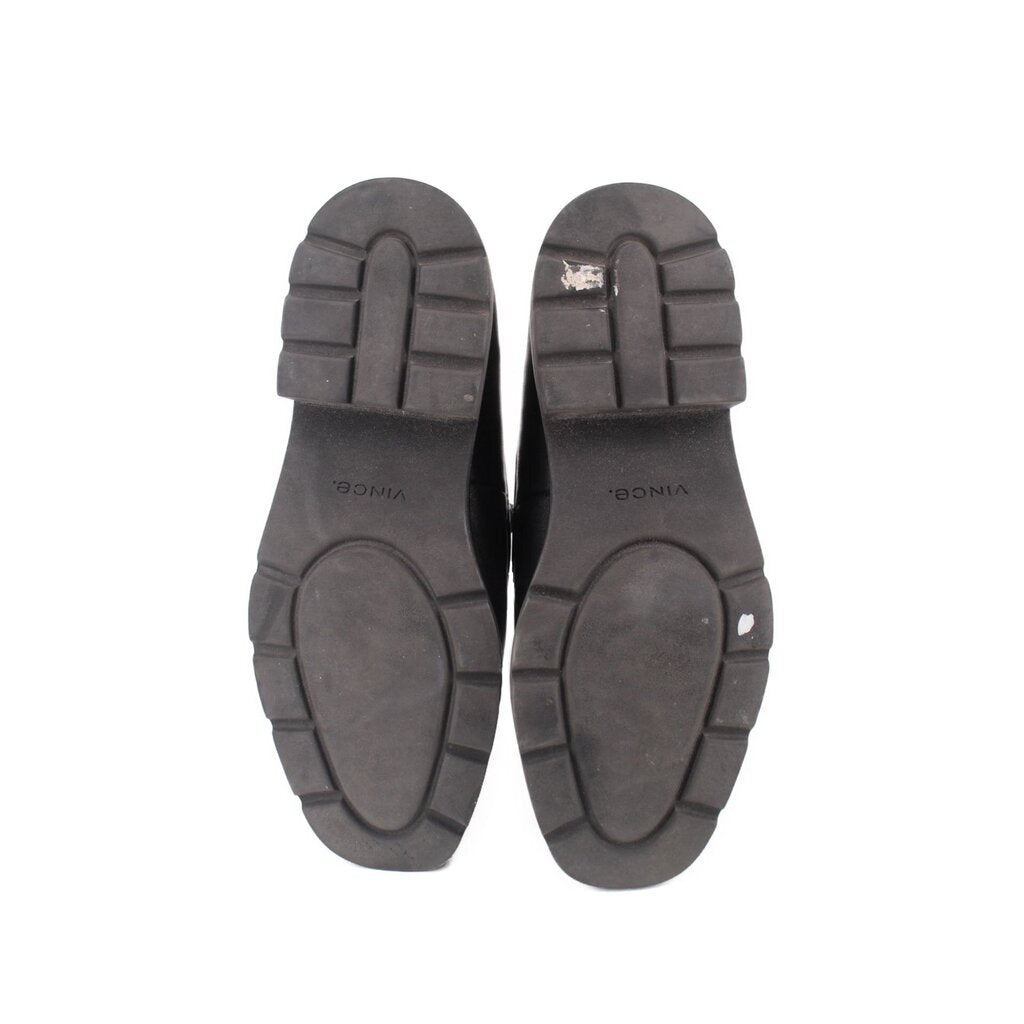 Outsoles of black slip-on loafers with textured rubber tread and circular traction patterns