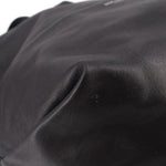 Close-up of black drawstring tote bag texture with stitched seam across front.