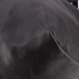 Close-up of black drawstring tote bag leather panels and subtle creasing near seam.