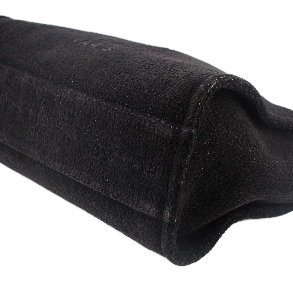 Black CHANEL tote bag corner with stitched fabric seam and rounded base