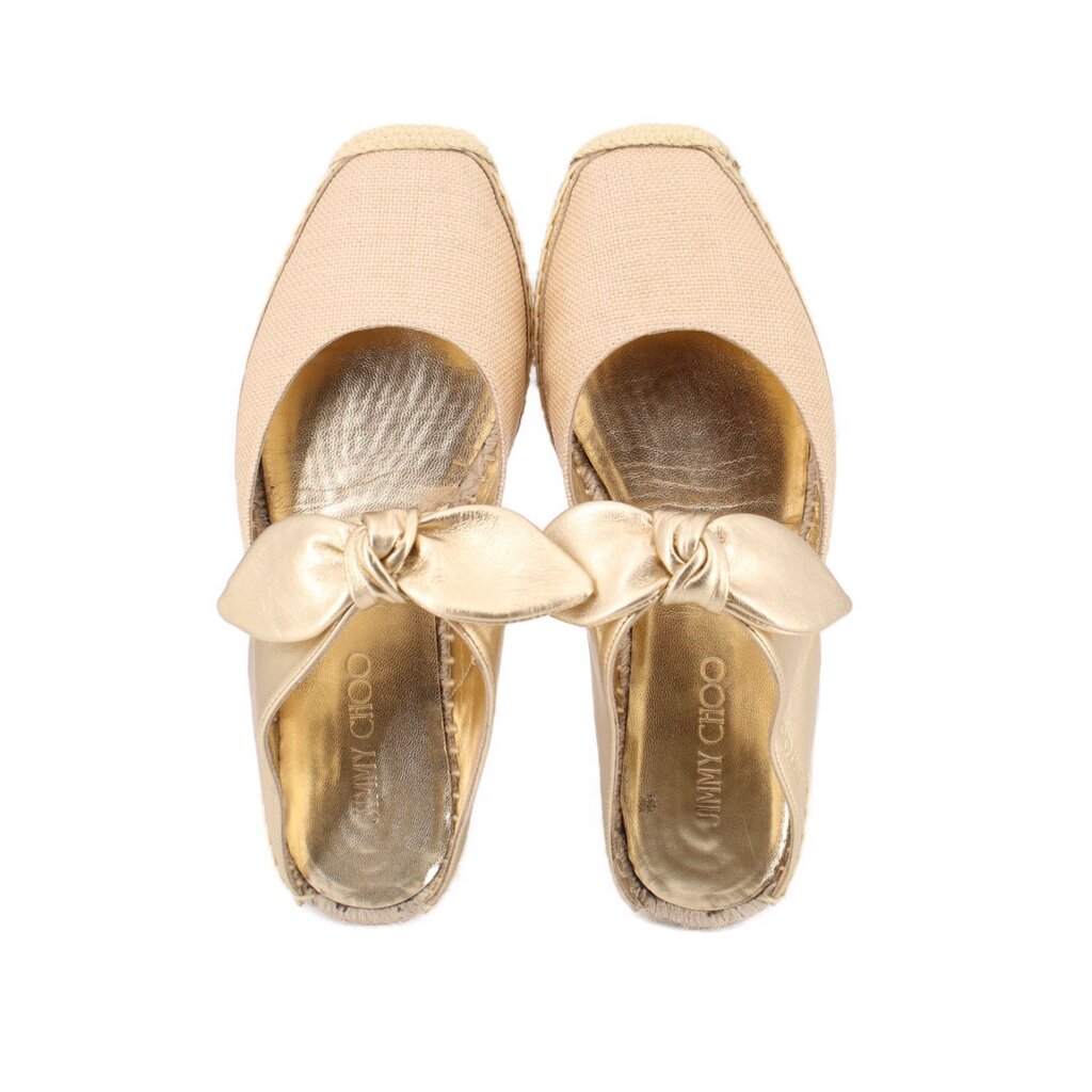 Pair of beige espadrille flat shoes with gold bow and metallic gold insoles