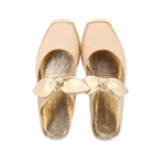 Pair of beige espadrille flat shoes with gold bow and metallic gold insoles