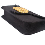 Black crossbody bag corner view with gold-tone logo emblem and textured fabric panel