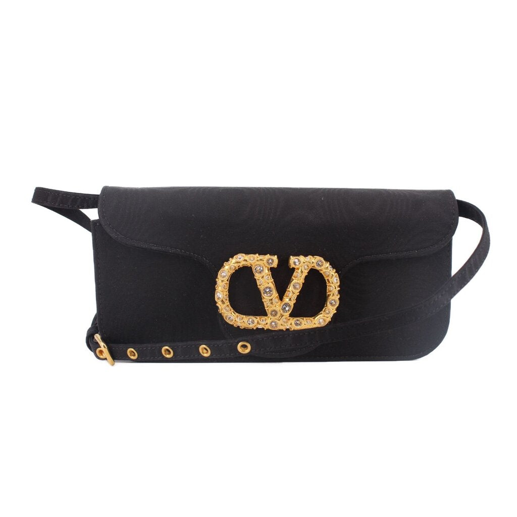 Black crossbody bag with gold-tone logo clasp and studded trim along the front flap