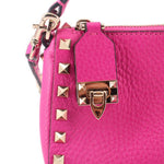 Pink crossbody bag front with gold-tone buckle hardware and small square Rockstuds