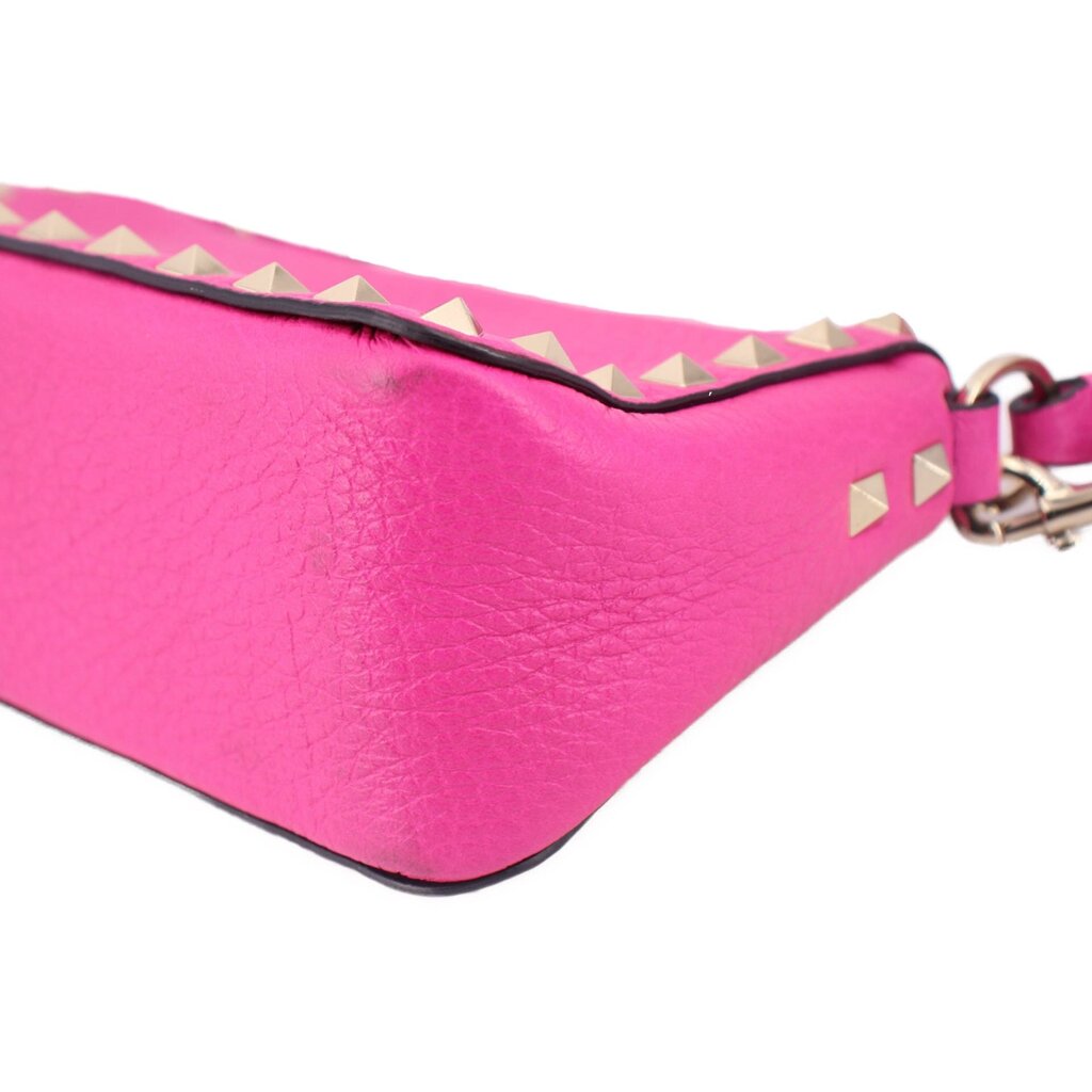Pink pebbled leather crossbody bag corner with gold-tone studs and trim strap