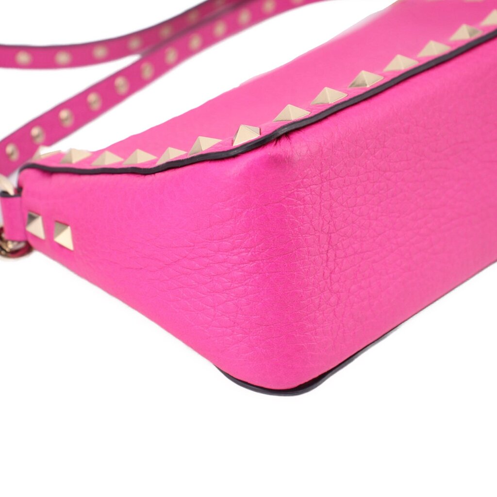 Pink crossbody bag with triangular gold studs along the trim strap and bottom edge