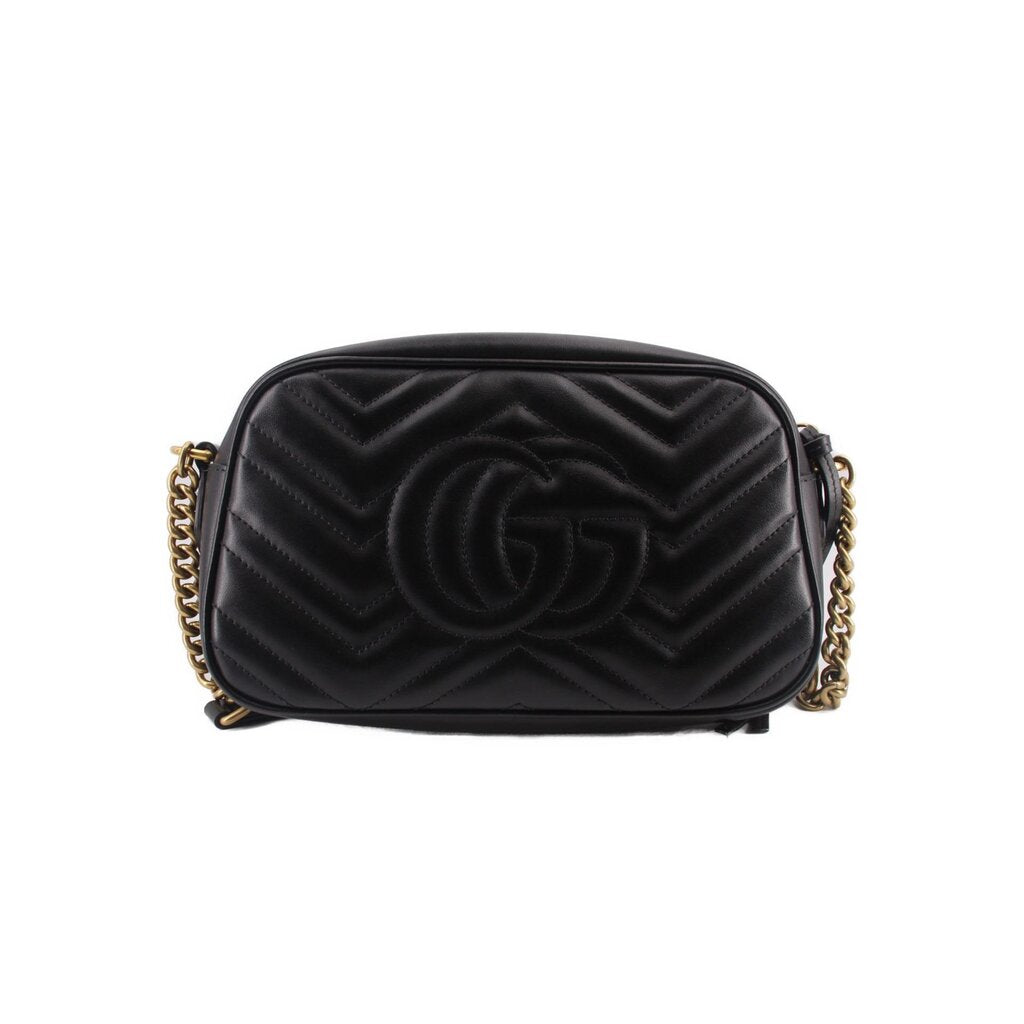 Black quilted camera crossbody bag with raised GG logo pattern and gold-tone hardware.