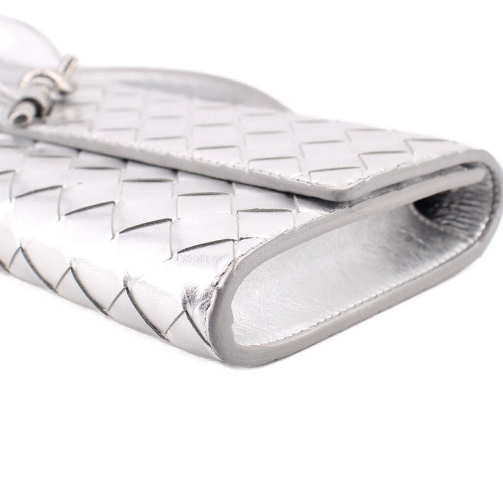 Silver metallic clutch corner close-up with woven pattern and folded edge