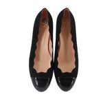 Pair of black wedge flats with pointed glossy toe and tan interior