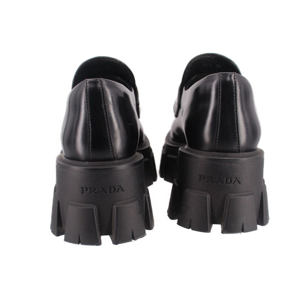 Black loafer heels with PRADA logo and chunky lug outsole, rear view