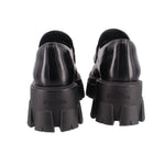Black loafer heels with PRADA logo and chunky lug outsole, rear view