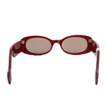 Red oval sunglasses with clear temples and gold logo detail at hinges