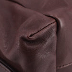 Brown leather crossbody bag close-up showing stitched seam and textured grain