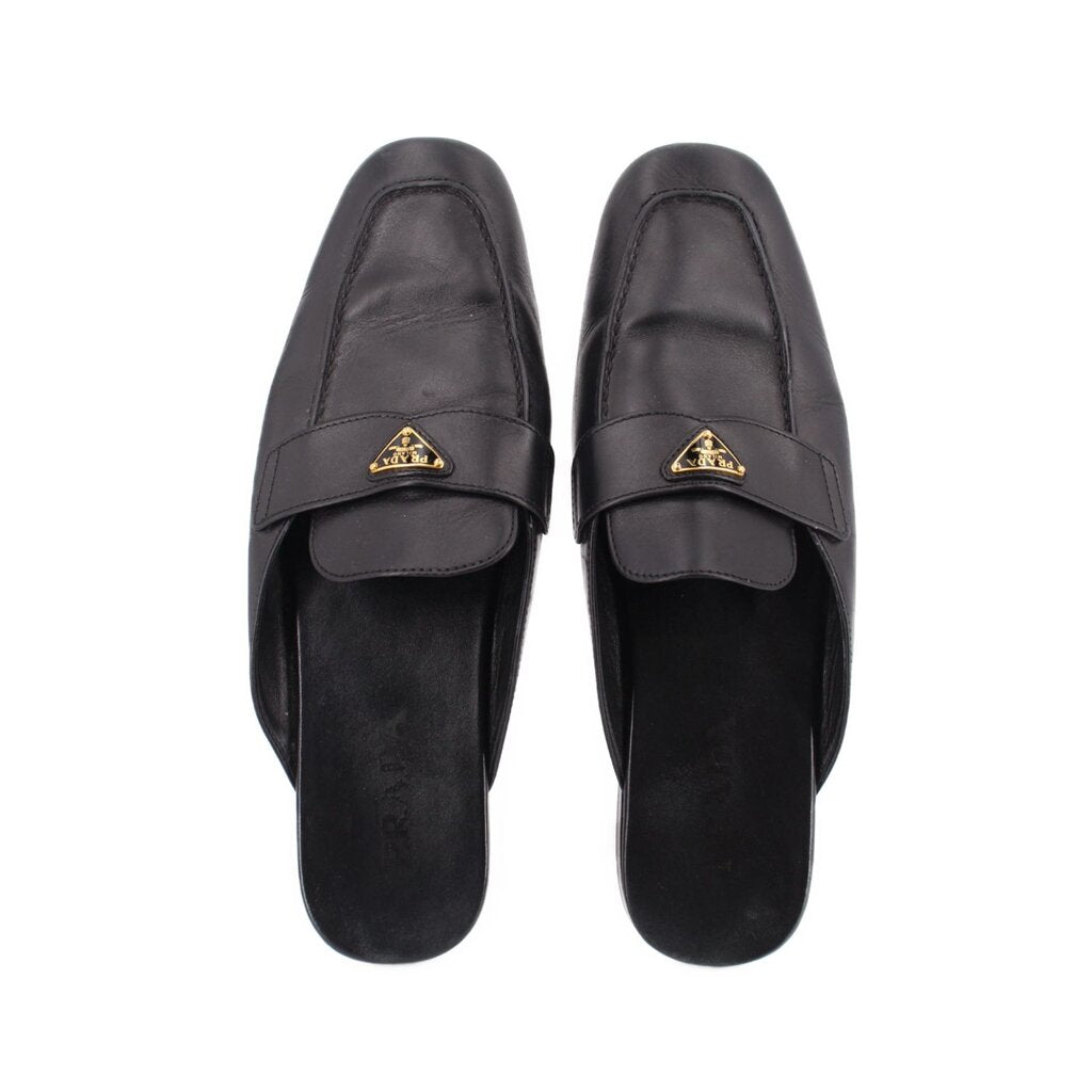 Black leather slide loafer, front view, with gold PRADA logo buckle