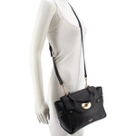 Black leather crossbody bag worn on mannequin, front flap and shoulder strap visible