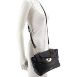 Black leather crossbody bag worn on mannequin, front flap and shoulder strap visible