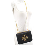 Small black crossbody bag with gold logo flap and braided chain strap on model