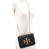 Small black crossbody bag with gold logo flap and braided chain strap on model