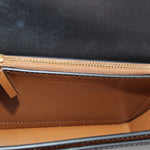 Interior of black crossbody bag with tan lining and gold zipper trim