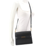 Black leather crossbody shoulder bag with front flap, gold logo tab, and chain strap
