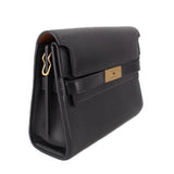 Black leather shoulder bag side view with front flap and gold-toned logo tab
