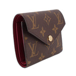 Louis Vuitton Victorine monogram wallet side view with red interior lining and gold snap