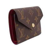 Louis Vuitton Victorine monogram wallet side view with red interior lining and gold snap