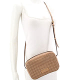 Tan perforated crossbody bag worn across body on model with adjustable strap