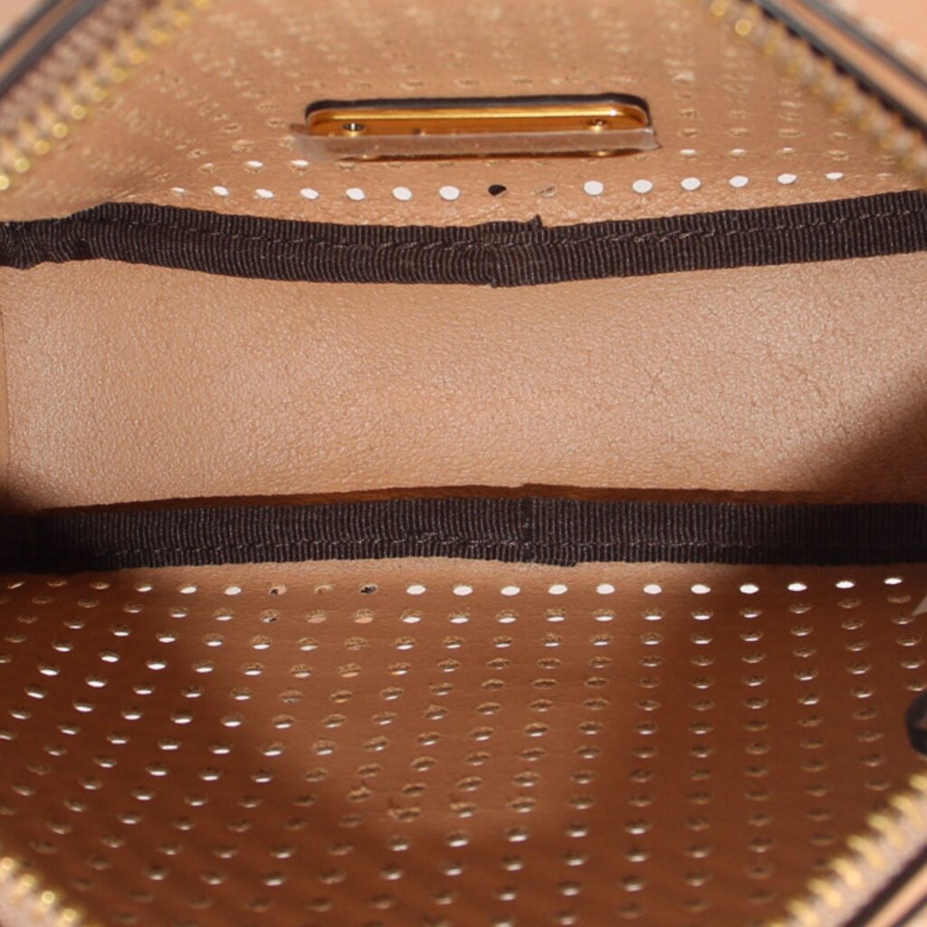 Inside view of tan perforated crossbody bag showing fabric lining and metal zipper tab