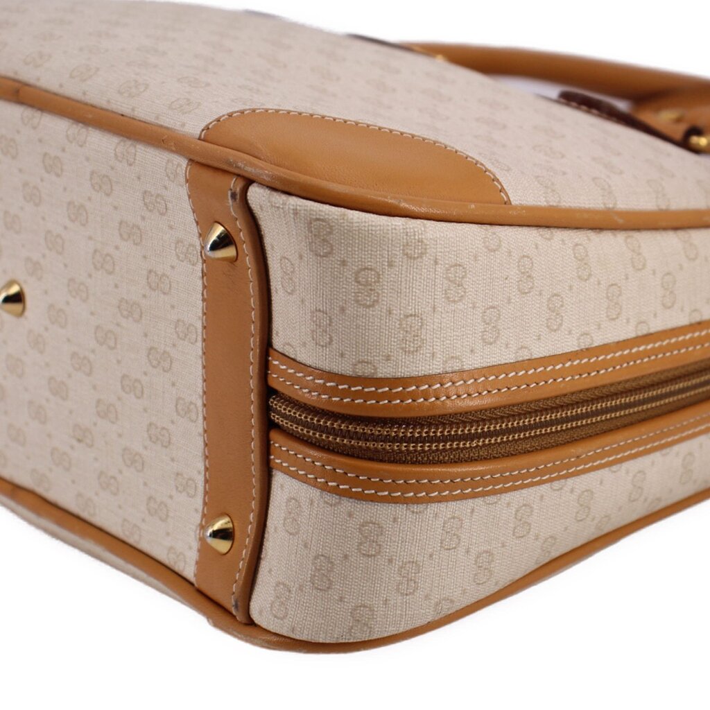 Beige monogram canvas bag corner with tan leather piping, rivets, and double-zip detail