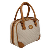 Beige canvas tote-style handle bag with tan leather strap and circular front logo patch