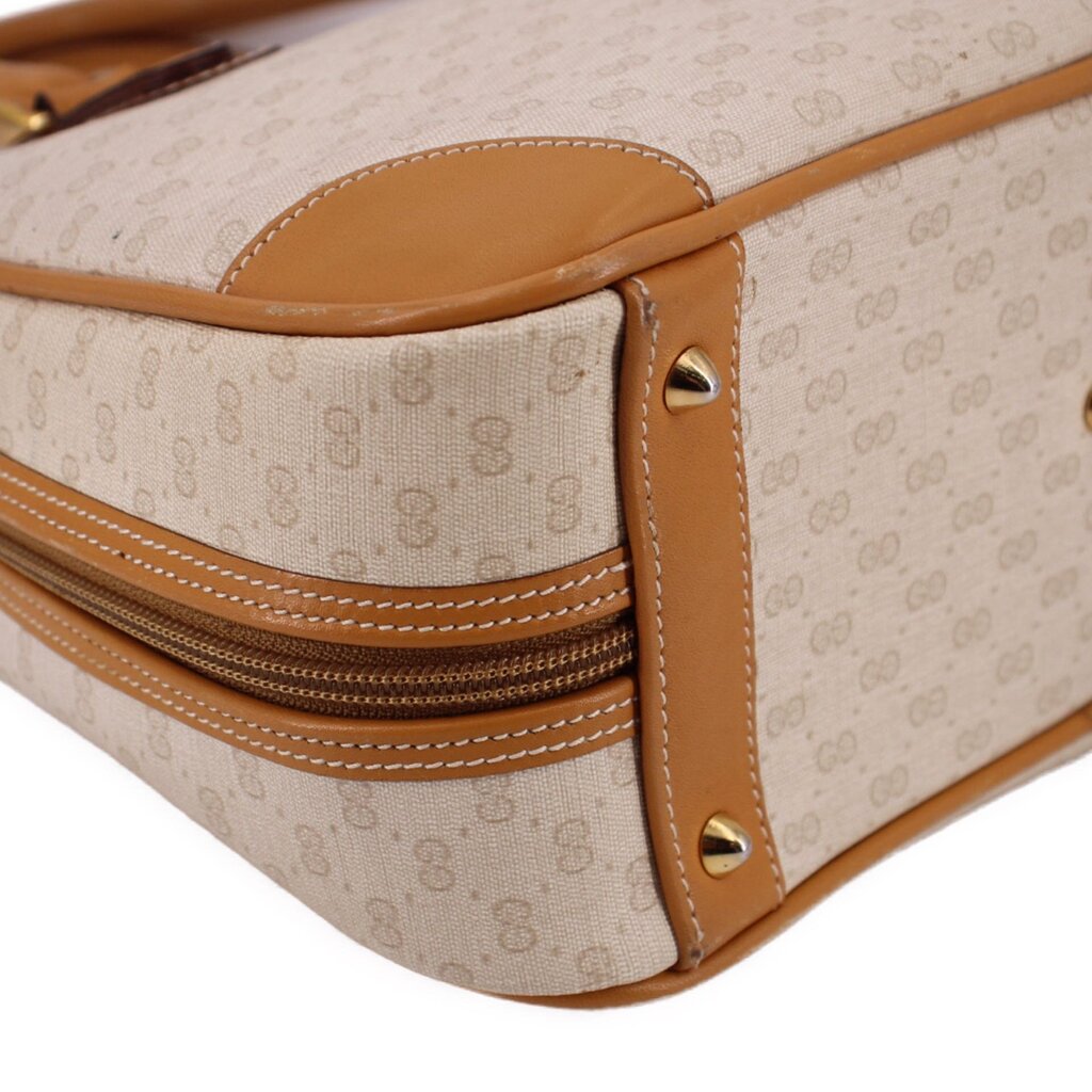 Beige canvas bag side view with tan leather gussets, stitched piping, and riveted strap