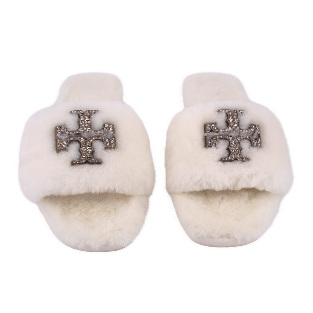 Cream shearling slide slippers showing front jeweled cross emblem, pair