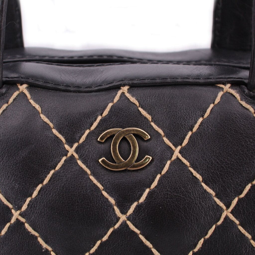 Black leather handle bag with diamond lattice stitching and CHANEL logo plaque