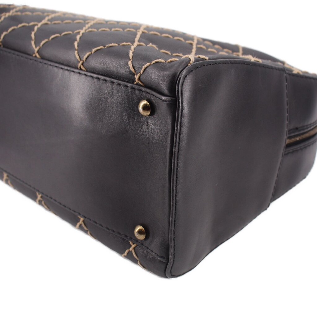 Black handbag corner with gold-tone snap studs and quilted stitching along the base