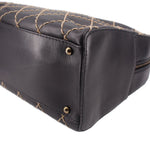 Black handbag corner with gold-tone snap studs and quilted stitching along the base