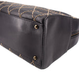 Black handbag corner with gold-tone snap studs and quilted stitching along the base
