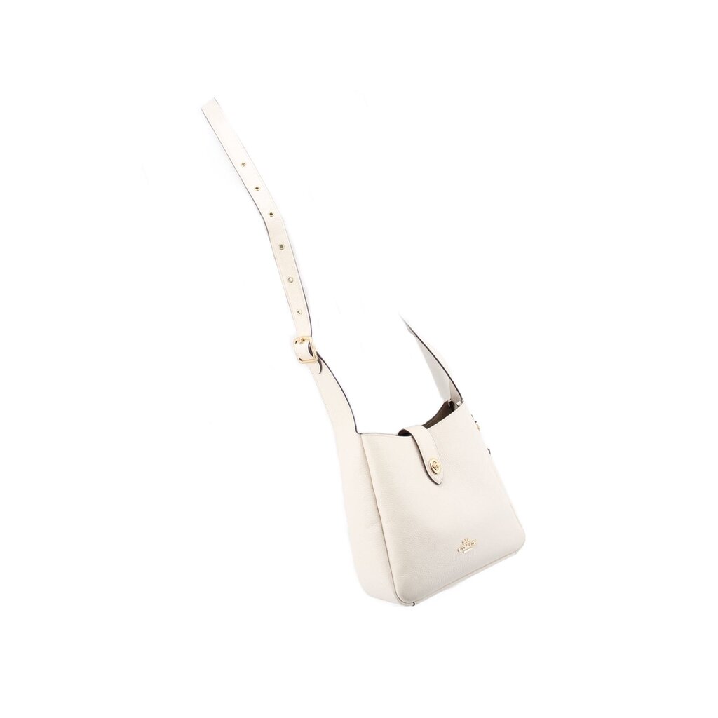 Cream mini crossbody bag hanging from adjustable strap with gold-tone button detail.