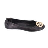 Black leather ballet flats, side view with gold logo medallion on toe
