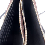 Interior of double-zip crossbody pochette with black lining and gold zipper trim