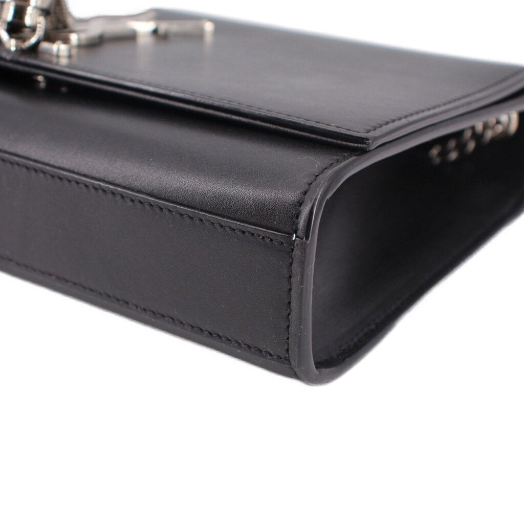 Black leather crossbody bag corner detail with stitched edge and clasp hardware