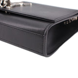 Black leather crossbody bag corner detail with stitched edge and clasp hardware